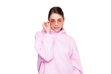 Happy young woman in casual pink hoodie adjusting glasses isolated on white, fashion.