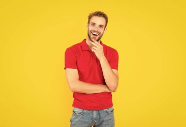 Kendine güvenen ve yakışıklı, tıraşsız adam. Erkek modası. Erkek güzelliği. Kırmızı gömlekli kıllı adam. Sarı arka planda sakallı genç bir adam. saç ve sakal bakımı.