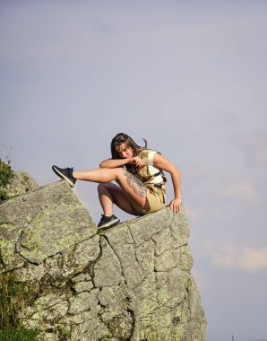 Manzaranın tadını çıkar. Turist yürüyüşçü kız uçurumun kenarında dinleniyor. Tehlikeli rahatlama. Olağanüstü bir kavram. Dünyanın kıyısında. Kadın yüksek dağlarda uçurumun kenarında oturuyor mavi gökyüzü arka planında. Huzurlu bir yürüyüş..