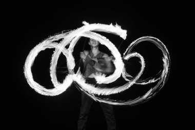 Erkek ateş dansçısı yanan sopa çeviriyor hareket halinde parlak izler yaratıyor..