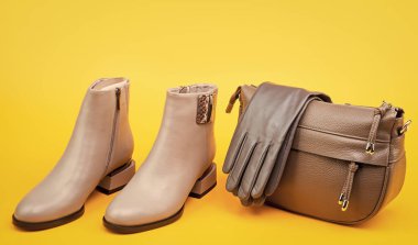 Deri bej çizme eldivenler ve sarı arka planda çanta, moda..