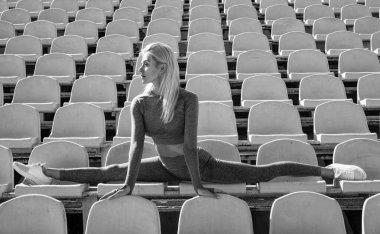 Mükemmel atış. Spor giyim antrenmanındaki atletik bayan stadyumda ikiye ayrıldı. Kasları ısıtıyor. Kadın esnek vücut. Yoga ve pilates. Spor, sağlıklı yaşam tarzı. Spor salonu koçu. seksi kadın dışarıda geriniyor.