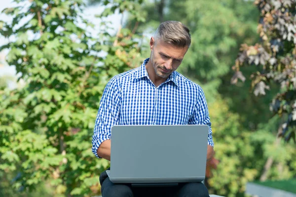 concentrated freelancer working on laptop. man freelancer outdoor. business freelancer with pc.