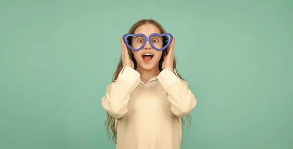 childhood happiness. fancy party look. happy funny kid in glamour eyeglasses on blue background. funky teen girl having fun. shocked child in party glasses. fashion accessory. going crazy.