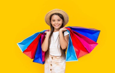 happy teen girl with shopping bags on yellow background.