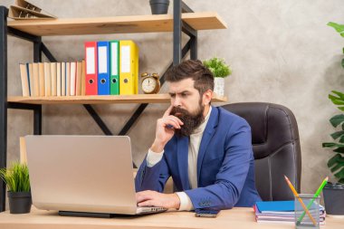 Serious professional man in suit working on work computer in office, employee.