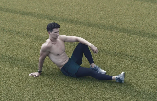 Muscular guy makes sit on grass. Shirtless sportsman resting after workout. guy sitting on grass. pleasure resting relax. sporty lifestyle concept. Relaxed sexy topless male sitting on grass.