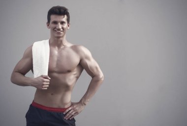 Güçlü kollar, pazı ve dayanıklılık atlet. Çıplak gövde altı paketi ve AB Fitness ve spor ile olan adam. Hijyen ve sağlık kavramı. Gri arka plan üzerinde havlu ile gülümseyen sporcu.