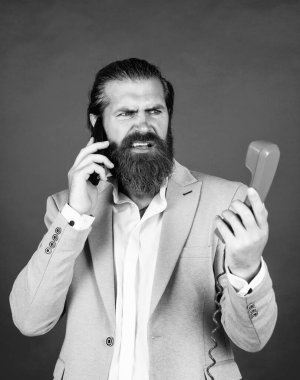 Sakallı hippi retro telefon kullanıyor. İletişim konsepti. Bıyıklı vahşi yakışıklı adam akıllı telefondan konuşuyor. Ara ve konuş. Modern ve klasik teknoloji. Aydınlan..