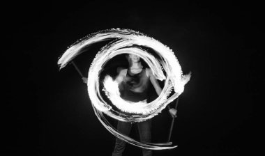 Dişi ateş dansçısı yanan sopayı çeviriyor hareket halinde parlak izler yaratıyor..