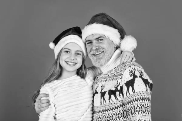 new year is here. bearded dad and small girl santa hat. funny knitted sweater. father and daughter celebrate christmas. xmas party together. they love family holiday. winter xmas mood.