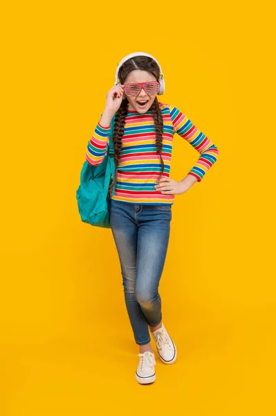 Music school. Teen girl singing along to music after school yellow background, music.