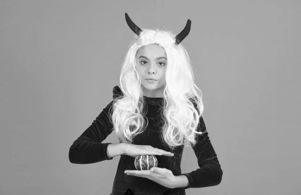 one little thing. kid hold pumpkin. traditional holiday food and autumn harvest. childhood happiness. teen girl ready to celebrate costume party. happy halloween. child in devil horns and white hair.