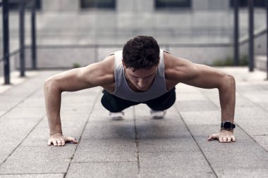 Beyaz tenli sporcu şınav çekiyor. Fitness antrenmanı. Açık havada şınav çek. Spor kıyafetli genç yakışıklı şınav çekiyor. Baldır ve kalça kasları için egzersiz yapıyor. mekik çeken yakışıklı adam..