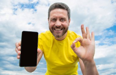 cheerful man presenting screen of smartphone with copy space.