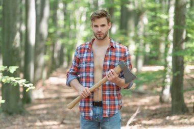 Unshaven axeman man in lumberjack style standing with axe forest background.