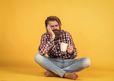 Uykulu, yorgun adam. O bir kahve molası veriyor. Fincandan su içen yakışıklı bir yetişkin. Bir fincan kahve ya da çay. Yaşam tarzı konsepti. Kahveli yakışıklı hippi..