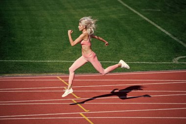 Atletik bayan sprint 'te yarışıyor. Spor, sağlıklı yaşam tarzı. Spor salonu açık havada. Koşucu pistte hızlı koşar. Enerjik ve sportif. Maraton hız enerjisi. Hareket halindeki kadın.