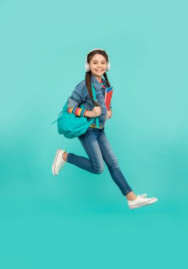 Happy girl jumping blue background, education. Energetic teenage girl in midair. School education. Informal and non-formal education.