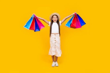 amazed teen girl with shopping bags on yellow background. full length.