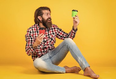 Hoşuma gitti. Beyaz bardak tutan yakışıklı sakallı adam. Bardakla içecek. Çay ya da kahve içmek. Günaydın. Evde sabah havası var. İlham konsepti. hippi adam kahve içer..