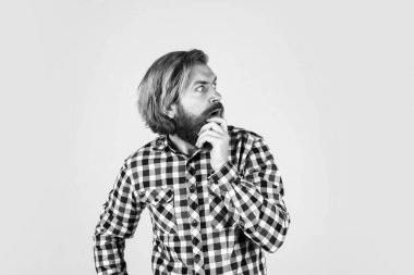 Şaşırmış, vahşi, sakallı, kareli gömlek giyen, gür sakallı, gerçek duyguları olan bir adam..