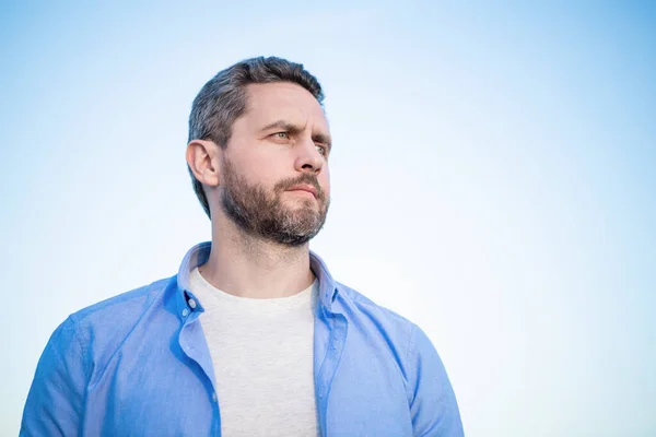 pensive man face standing peaceful. pensive man in shirt outdoor. pensive man on sky background.