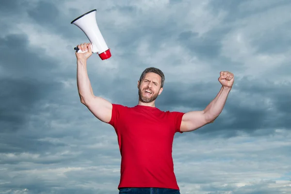 man in red shirt with loudspeaker on sky background.