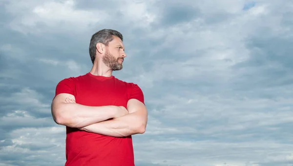 Confident man sky background. Serious man keeping arms crossed. Grizzled man in casual outdoors, copy space.