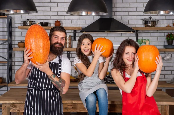 happy parents with kid cook pumpkin together in kitchen, family.