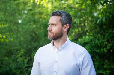 Handsome professional guy in white shirt looking aside natural background.