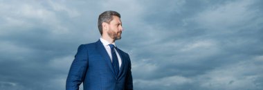 Portrait of businessman looking aside. Businessman in suit. Serious grizzled businessman sky background, copy space.