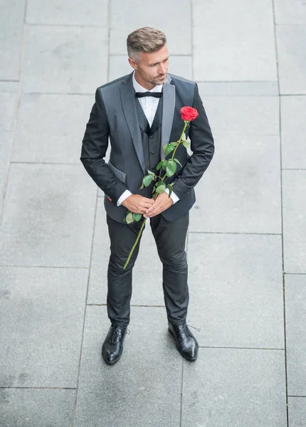 engagement date. adult tuxedo man celebrates engagement. man with rose gift for engagement.