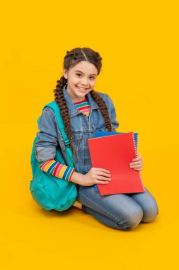Happy girl teenager sitting on knees yellow background, school. September 1. School education. Back to school.