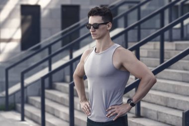 Motive olmuş güneş gözlüklü genç sporcu sabah koşusu için stadyumda hazır..