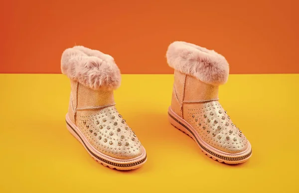 pair of fashionable winter beige ugg boots on yellow background, new pair.