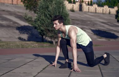 Başlama pozisyonu, adam atlet. Güneşli yaz gün açık havada yolda asfalt atlet. Maço eşofman ve spor ayakkabısı içinde kentsel peyzaj uygun. Hazır sabit git. Sağlıklı yaşam konsepti.