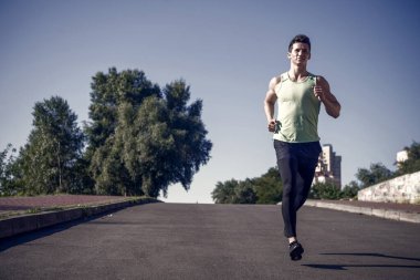Asfalt yolda mavi gökyüzü güneşli yaz gününde koşan adam. Başarı, hedef ve gelecekteki kavramı
