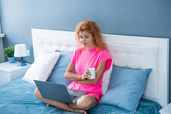 sceptic woman freelancer with coffee work at home on laptop. freelancer woman work at home. home work for freelancer. woman in bed with laptop.