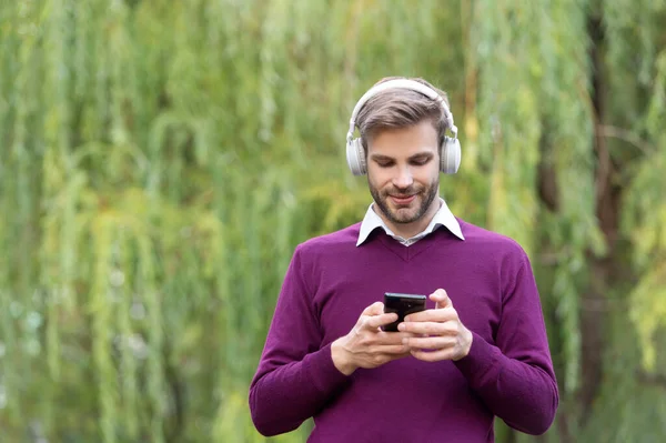 Giovane Uomo Positivo Ascoltare Musica Cuffia Chattare Telefono All Aperto — Foto Stock