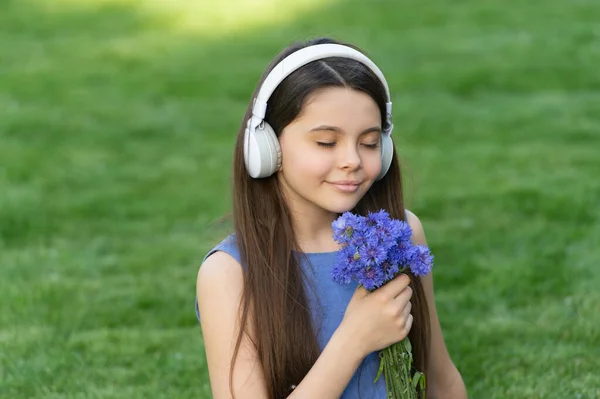 10代の女の子は音楽を聴く ワイヤレス音楽ヘッドフォンの子供です 子供は音楽の匂いの花を聞いて — ストック写真