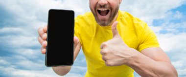 Akıllı telefon ekranı ile fotokopi alanı sunan adamın kırpılmış görüntüsü. başparmak yukarı.