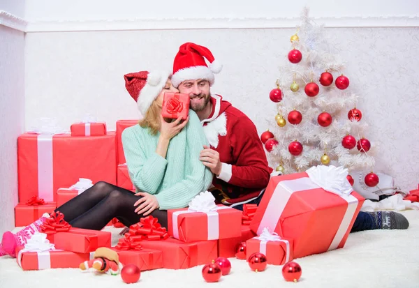 Opening christmas present. Pleasant surprise. Couple sit near pile of gift boxes and christmas tree background. Husband prepared christmas surprise. Couple in love enjoy christmas holiday celebration.