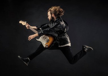 Rock müzik çalıyordu. Modaya uygun çılgın adam. müzik enstrümanı. Deri ceketli duygusal sakallı rockçı. Uzun saçlı bir adam elektro gitar çalıyor. Rock müzik tarzı. müzisyen gitarist atlıyor.