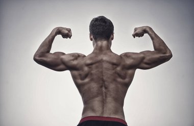 Gri gökyüzü üzerinde çıplak gövde ile sporcu. Vücut kas, pazı ve triceps gösterilen. Adam ya da yumruk, arkadan görünüm kollarını esneme sporcu. Fitness ve spor. Sağlıklı yaşam konsepti