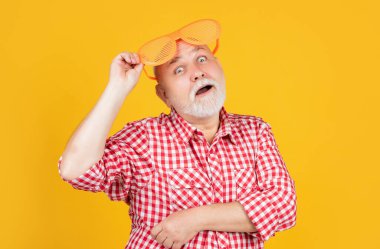 Sarı arka planda parti gözlüklü, kareli gömlekli yaşlı adam hayrete düştü..