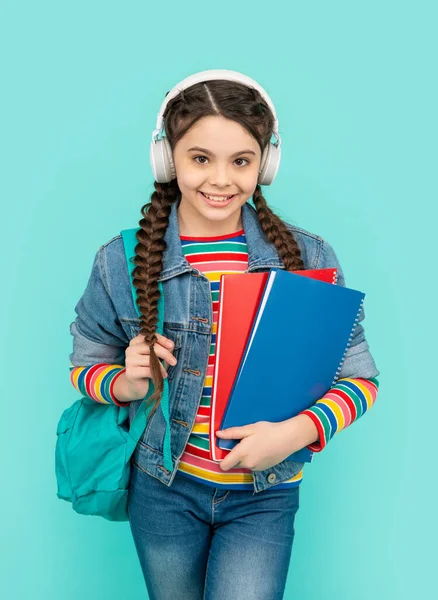幸せな女の子のオーディオコース青の背景に耳を傾ける ヘッドフォンでオーディオブックを聴く女子高生 リスニング力 学校教育 — ストック写真