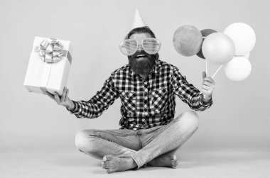Komik, vahşi, sakallı, kareli gömlek giyen, sakallı, bıyıklı parti balonları ve hediye kutusu olan bir adam..