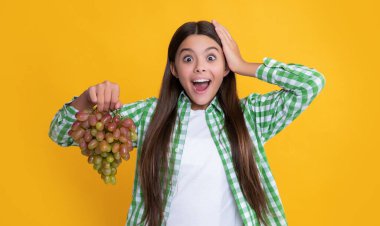 Sarı arka planda üzümlü şok olmuş bir çocuk. diyet.