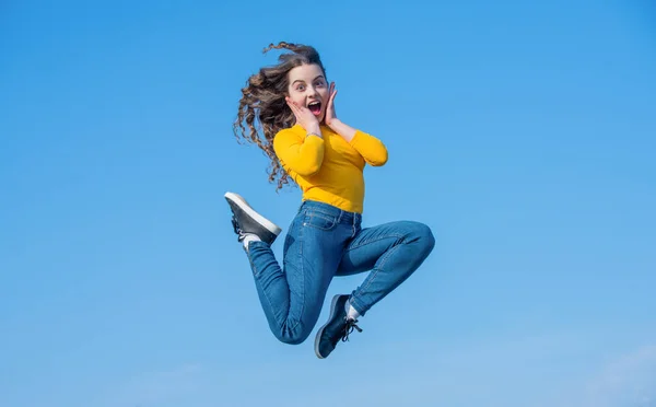 amazed teen girl jump high on sky background.